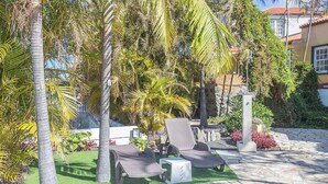 A patio area with two lounge chairs, a small table, and a decorative pillar. - Guestready - Colon Eva (Fuencaliente de la Palma)