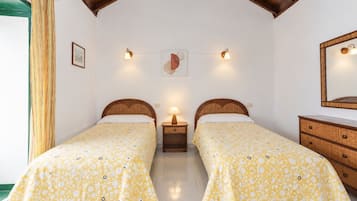 A room with two beds, a wooden dresser, a mirror, and wall-mounted lights.