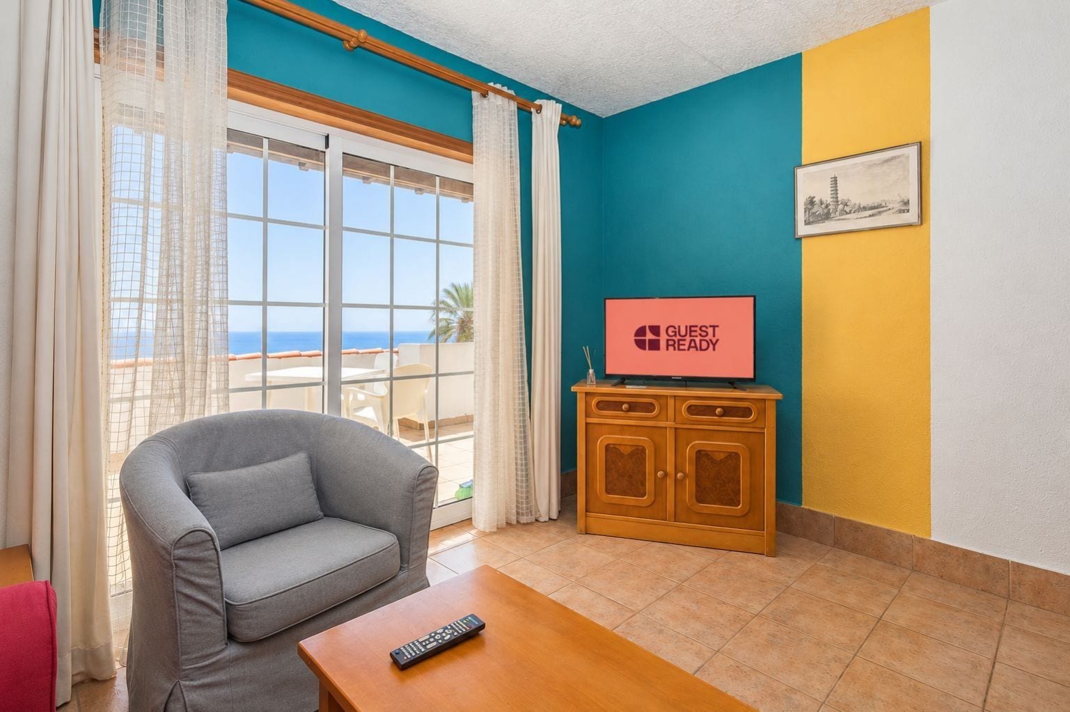 A room with a grey sofa, a wooden table, a TV on a stand, and a window with curtains.