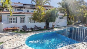 A swimming pool with a stone deck, lounge chairs, and a building with a tiled roof in the background. - Guestready - Colon Eva (Fuencaliente de la Palma)