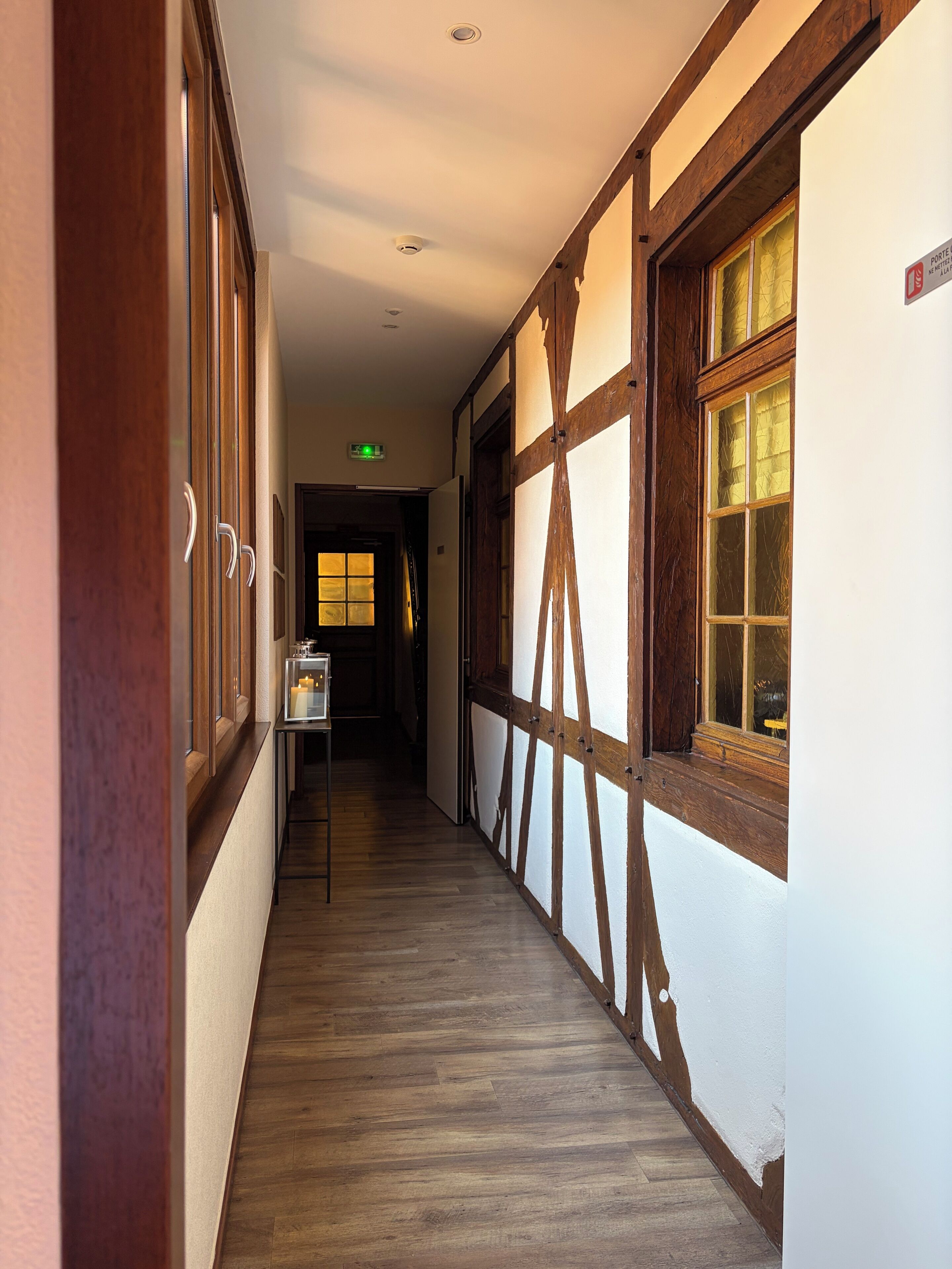Un couloir avec des poutres en bois, un plancher en bois et une fenêtre donnant sur un paysage agréable.
