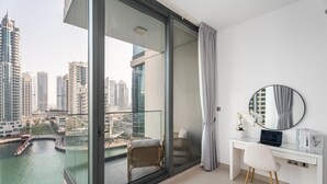 A modern apartment with a balcony, a city view, a desk with a laptop, and a round mirror. - Gala Guests - LIV Apartments Collection (Dubai)