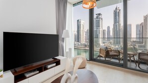 A modern living room with a large TV, a white console, and a decorative vase. - Gala Guests - LIV Apartments Collection (Dubai)