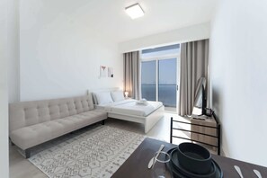 Une chambre d’hôtel moderne équipée d’un canapé, d’un lit, d’une table à manger avec couverts, d’une télévision et offrant une vue sur la ville.