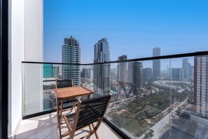 Un balcón con mesa y sillas, que ofrece vistas a un paisaje urbano con edificios altos.