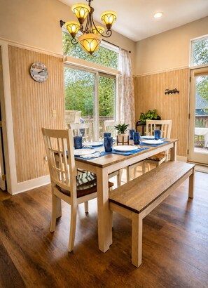 A dining area with a wooden table, chairs, and a bench. There is a window with curtains, a clock on the wall, and a chandelier. - Gray Fox Lakeview near wisp and attractions (McHenry)