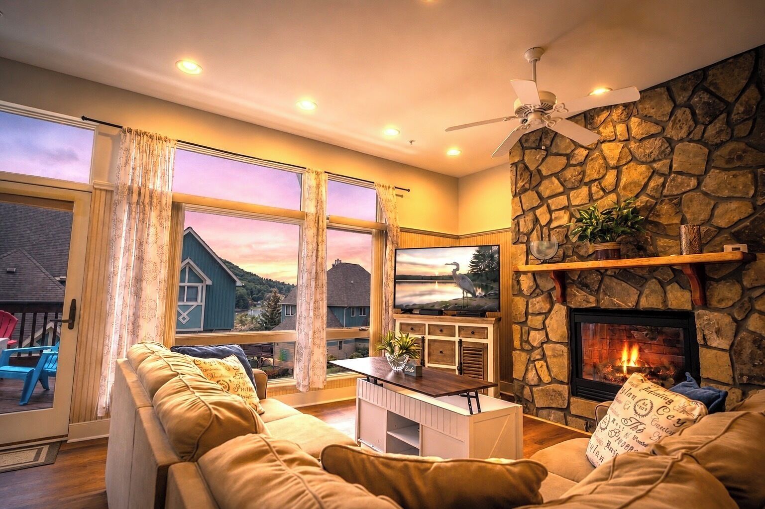 Una sala de estar con chimenea de piedra, televisor y sofá.