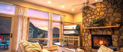 Una sala de estar con chimenea de piedra, televisor y sofá.