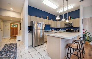 A modern kitchen with a central island, stainless steel appliances, and bar stools. - Gray Fox Lakeview near wisp and attractions (McHenry)