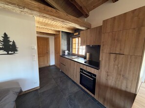 Eine moderne Küche mit Holzausstattung, einer schwarzen Arbeitsplatte und einem eingebauten Ofen.