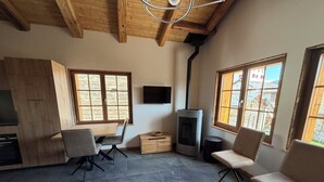 A modern interior with a fireplace, wooden ceiling beams, and large windows. - Le mazot - large studio with separate shower room (Lens)