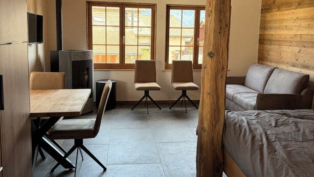 A cozy room with a bed, a wooden ceiling, a fireplace, and two windows. - Le mazot - large studio with separate shower room (Lens)