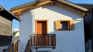 A two-story building with a wooden balcony, a staircase, and a door. - Le mazot - large studio with separate shower room (Lens)