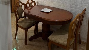 A dining area with a round table, four chairs, and a hanging light fixture.
