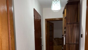 A hallway with a tiled floor, wooden doors, and a ceiling light fixture.