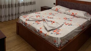 A bedroom with a wooden bed, a nightstand, a painting, and a ceiling fan.