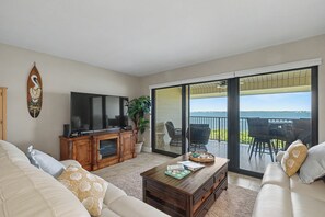 Un salon équipé d’un téléviseur, d’un canapé, d’une table basse et d’un balcon aménagé avec du mobilier d’extérieur.