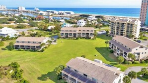 Un hotel sulla costa con diversi edifici, un prato centrale e vista sull'oceano.