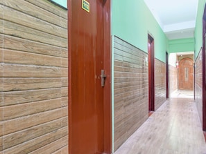 A hallway with wooden paneling, a red door with a number sign, and a green wall.