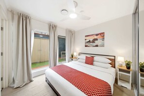 A hotel room with a bed, a ceiling fan, a painting, and a view of the outdoors. - Spacious 3-Bed Apartment in Canberra CBD (Canberra)