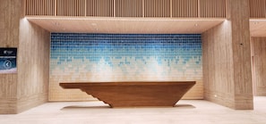 A modern bathroom with a wooden vanity, a blue mosaic wall, and a wooden ceiling.