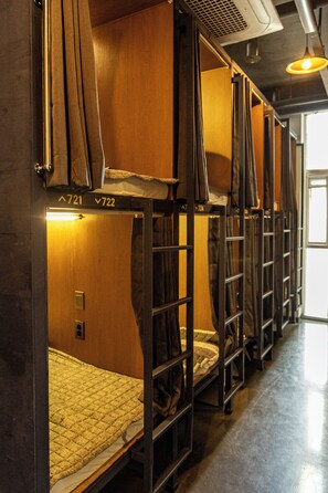 Bunk beds with numbers on the doors, a metal railing, and a light fixture on the ceiling. - Lazy Cube (Seoul)