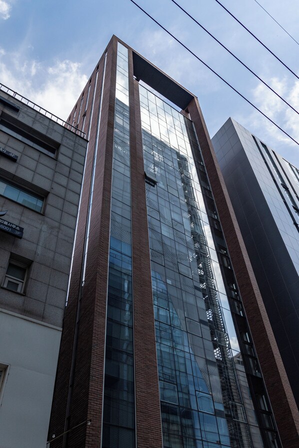 A tall building with a glass facade and brick accents. - Lazy Cube (Seoul)