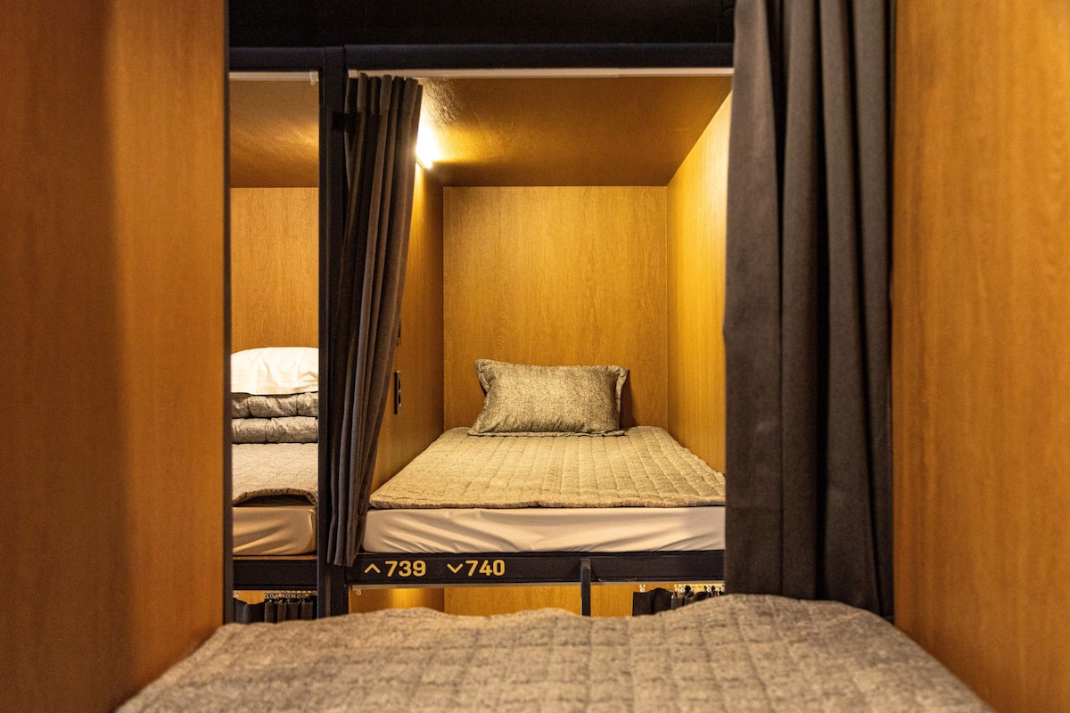 A single bed with a headboard, a bedside table, and a curtain.
