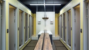 A long corridor with multiple doors, each leading to a bathroom with a sink and mirror.