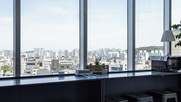 A room with large windows, a kitchenette, and a seating area with stools.