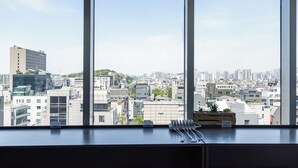 A cityscape view from a window with a table featuring a remote control, a tray, and utensils.