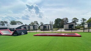 An outdoor area with artificial grass, a red trampoline, and a black and red play structure. - Wonderful private villa for 2 people with WIFI, A/C, pool, TV and terrace (Tholen)