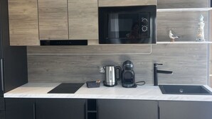 A modern kitchen with a built-in microwave, coffee maker, and sink. - Wonderful private villa for 2 people with WIFI, A/C, pool, TV and terrace (Tholen)