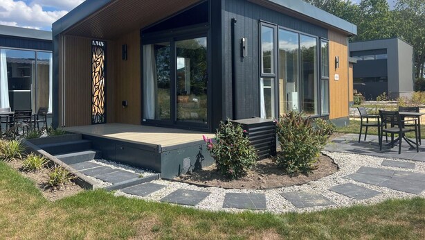 A modern building with a wooden facade, large glass windows, and a patio area with outdoor seating. - Wonderful private villa for 2 guests with pool, WIFI, A/C, TV and terrace (Tholen)