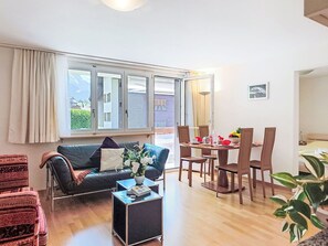 Ein Wohnzimmer mit einer Couch, einem Couchtisch und einem Essbereich mit Stühlen und Tisch.
