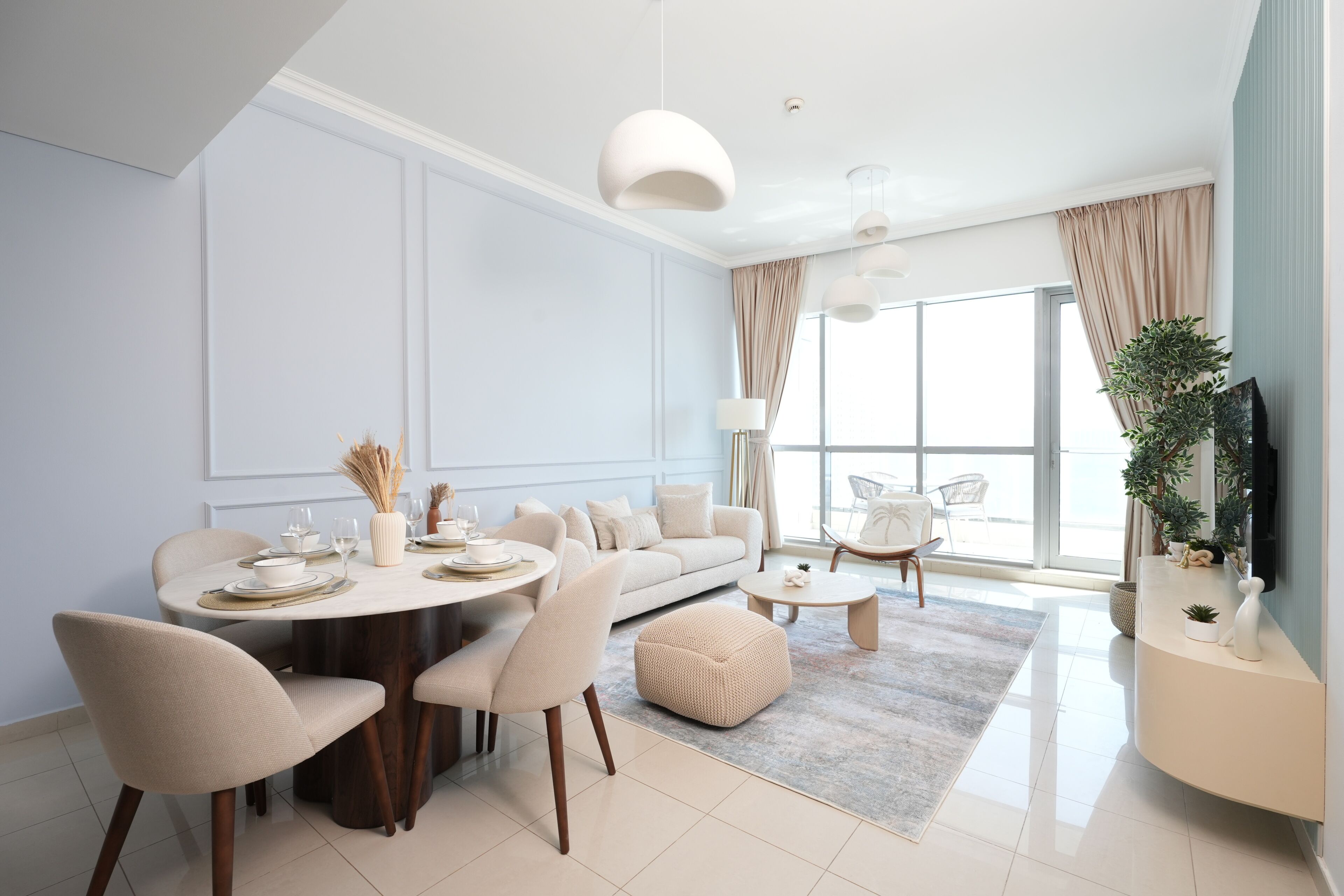 A modern living room with a dining area, large windows, and a flat-screen TV.