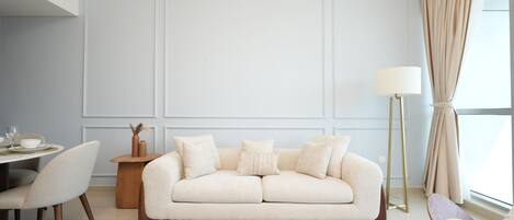 Una sala de estar moderna con un sofá, sillas, una mesa de centro y un comedor.