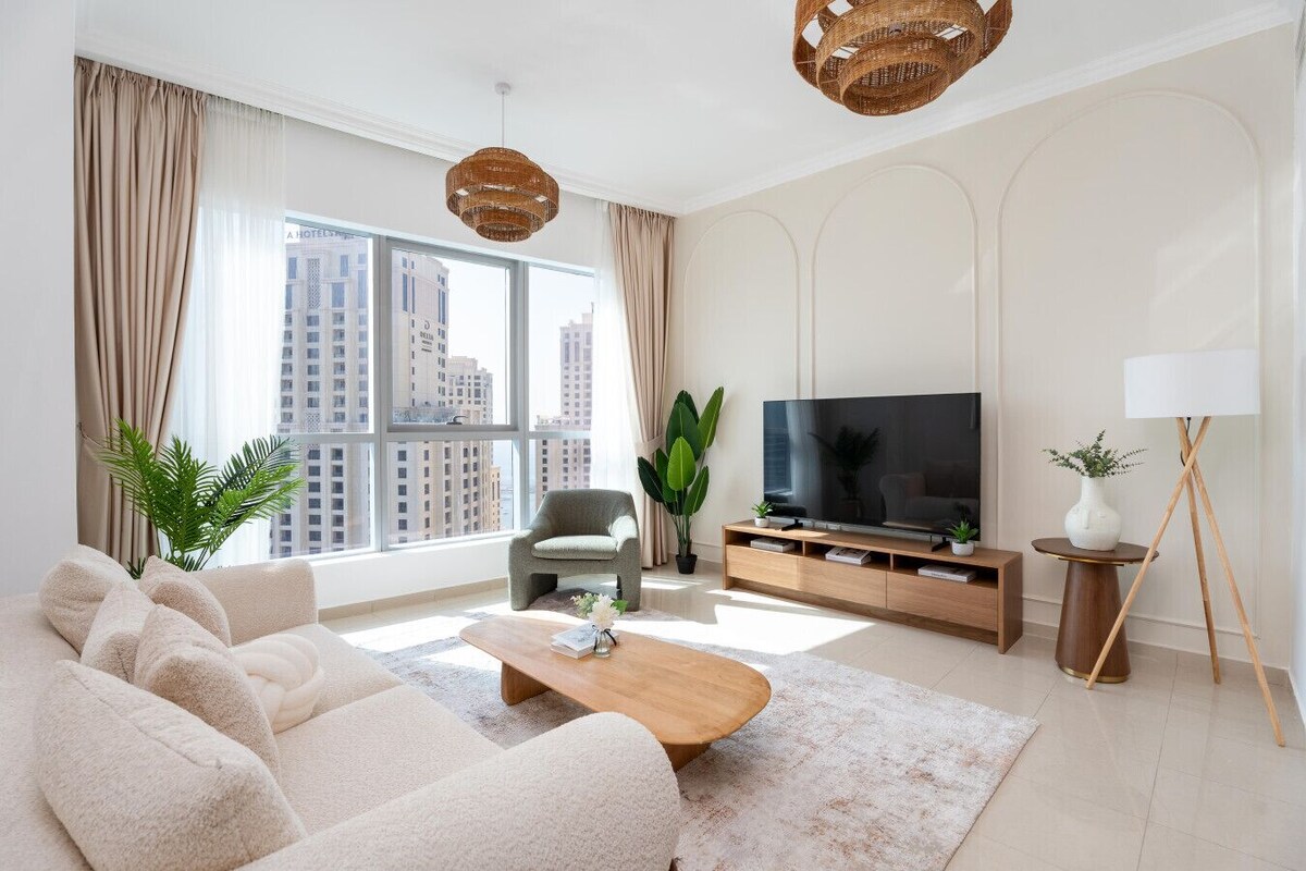 Ein modernes Wohnzimmer mit einer Couch, einem Couchtisch, einem Fernseher und einer Pflanze.
