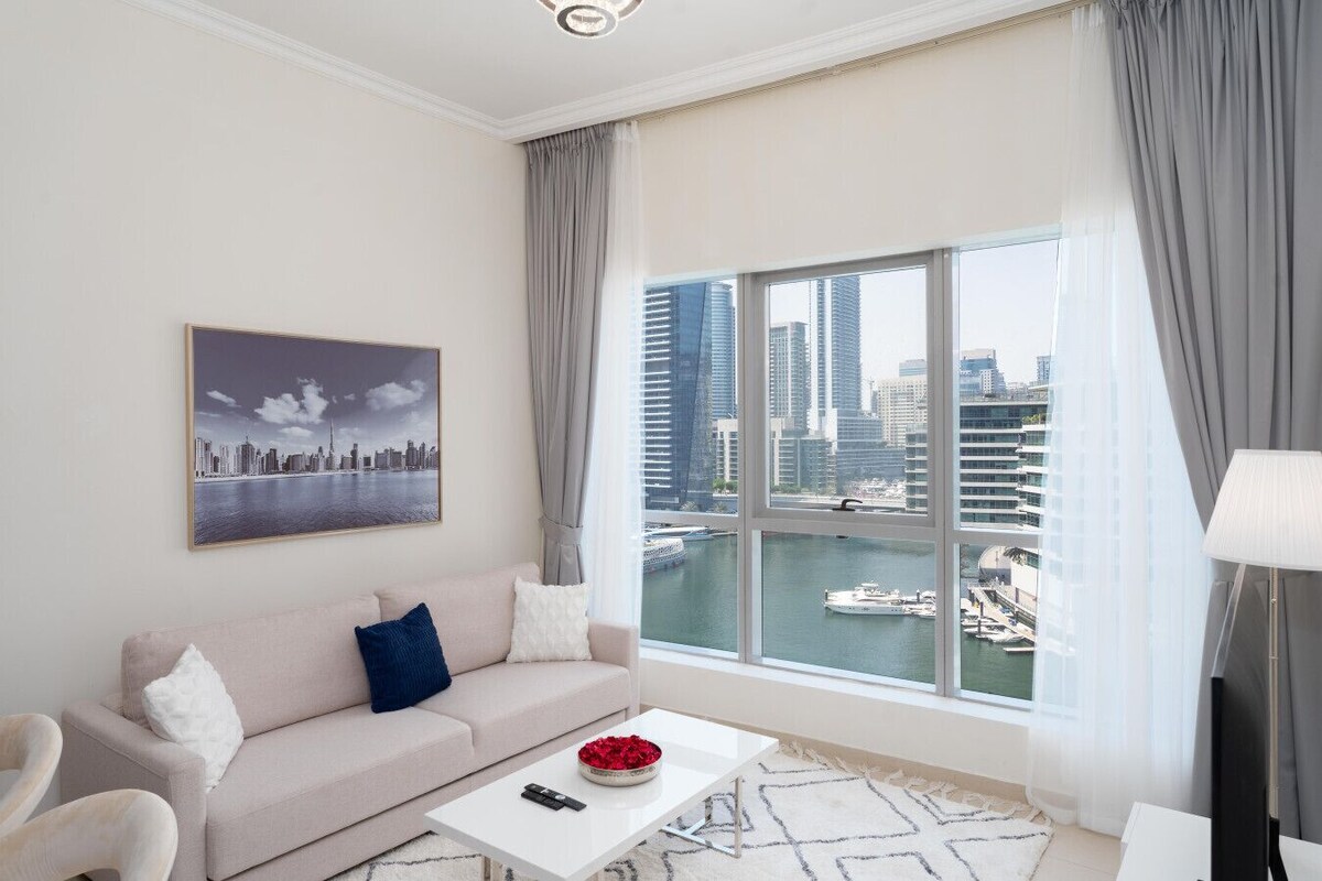 Ein modernes Wohnzimmer mit großem Fenster, einer Couch, einem Couchtisch und Blick auf die Stadt.
