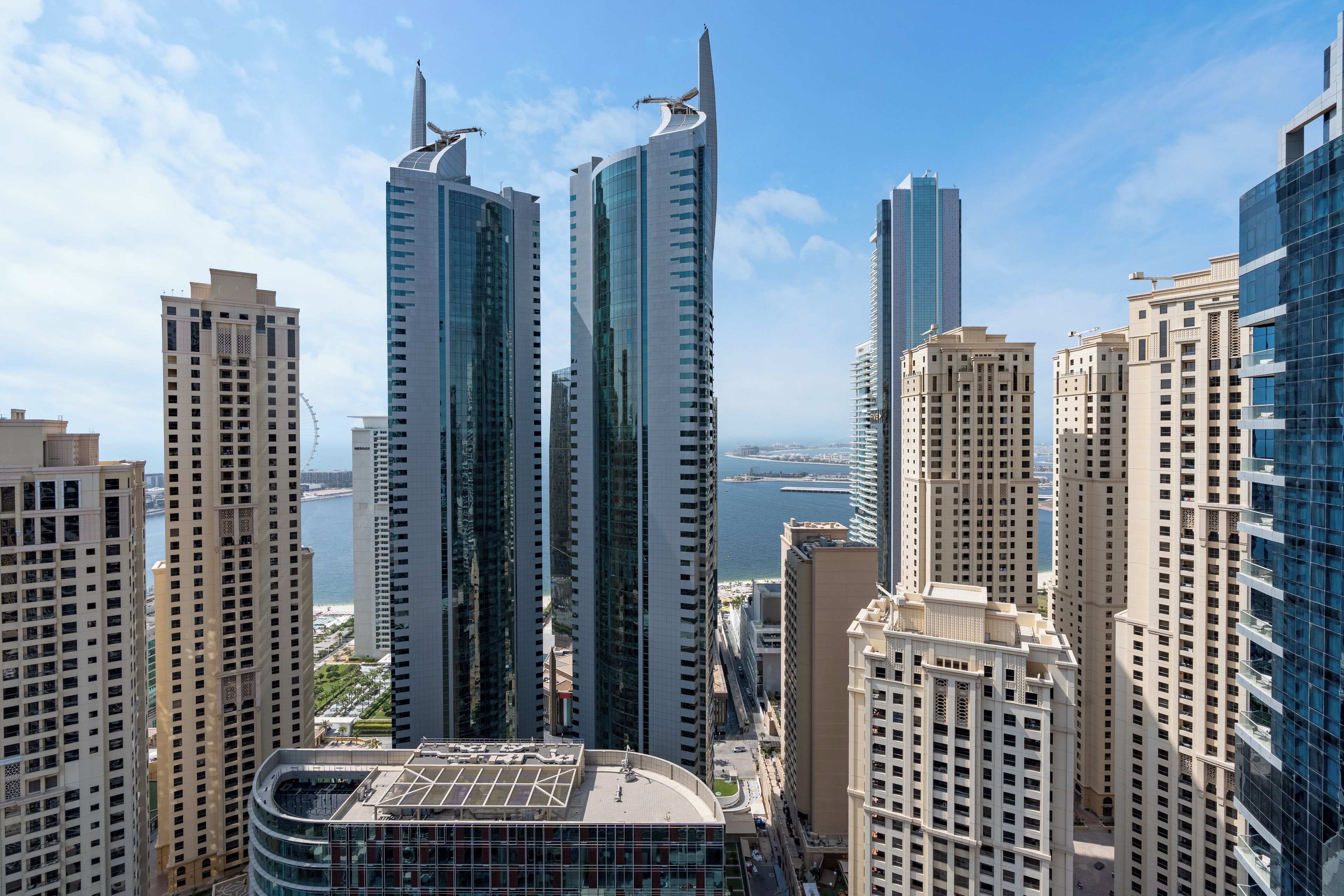 A high-rise building with a curved glass facade and a rooftop terrace.