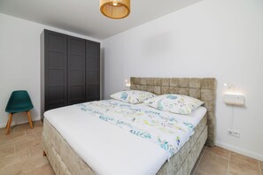 Ein Schlafzimmer mit Bett, Schrank, Sessel und Wandleuchte.