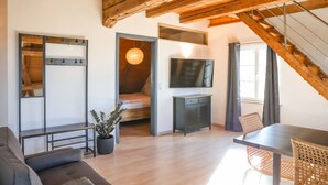 A loft-style room with a wooden ceiling, a bed, a TV, a dining table, and a staircase. - Apartment 'Ferienwohnung Wintersulgen' with Wi-Fi (Heiligenberg)