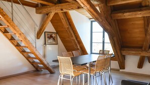 A dining area with a wooden ceiling, a table with chairs, and a staircase. - Apartment 'Ferienwohnung Wintersulgen' with Wi-Fi (Heiligenberg)