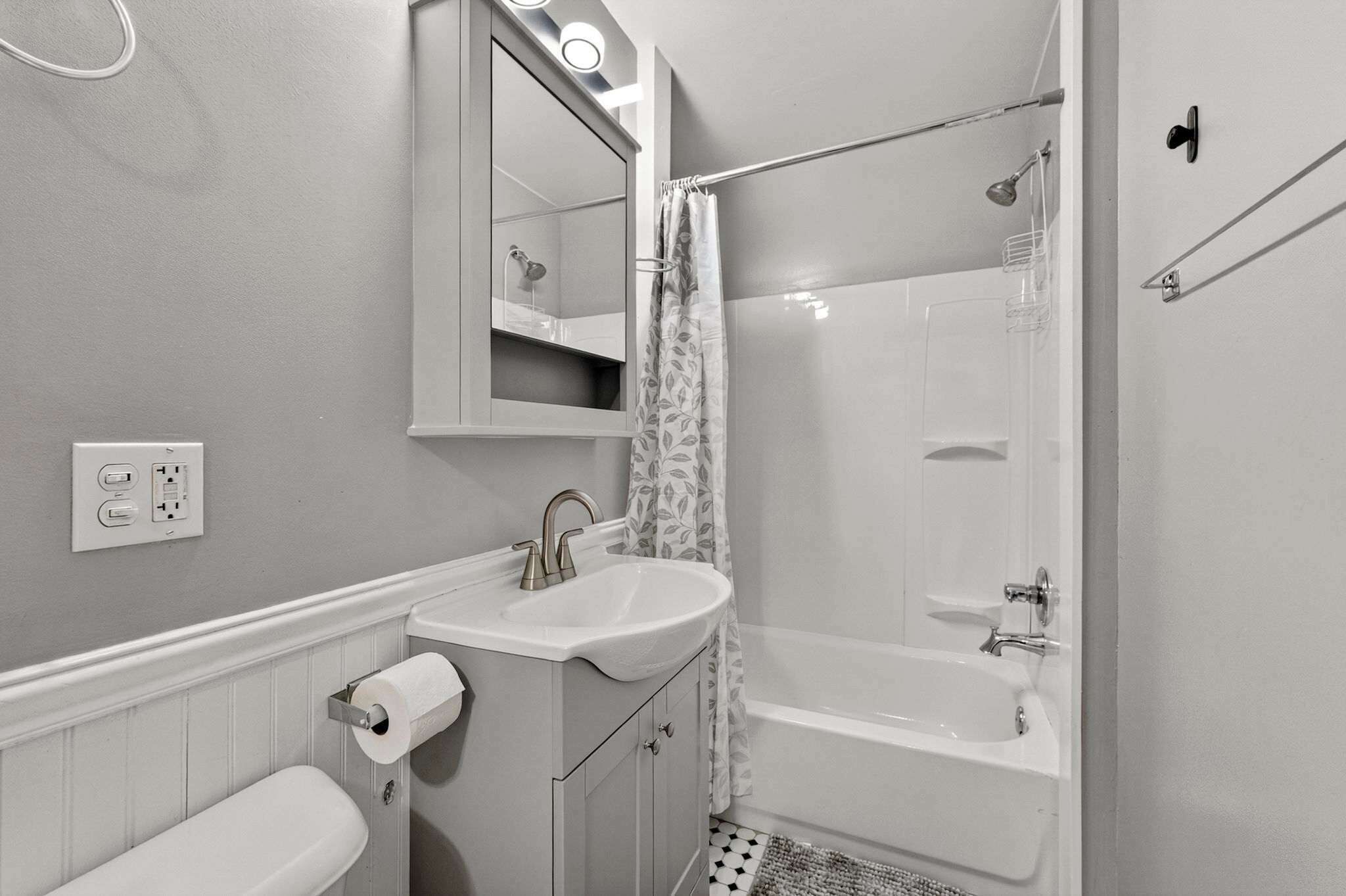 Een badkamer met een witte wastafel, spiegel, toilet en bad.