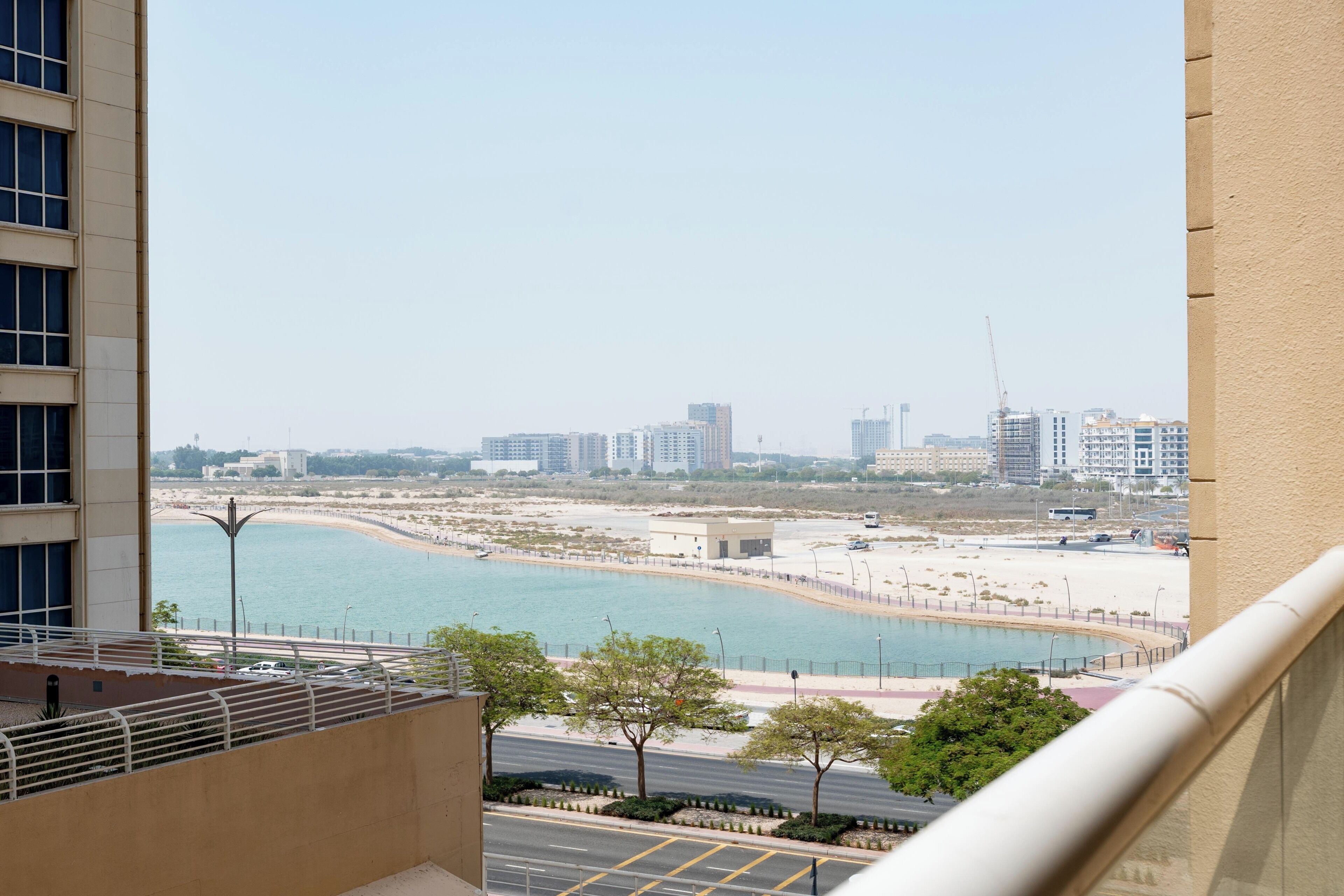 A view of a coastal cityscape with buildings, a beach, and a road.
