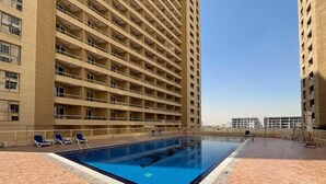 A rooftop swimming pool with lounge chairs, surrounded by high-rise buildings. - Gala Guests - Lakeside Tower Living (Dubai)