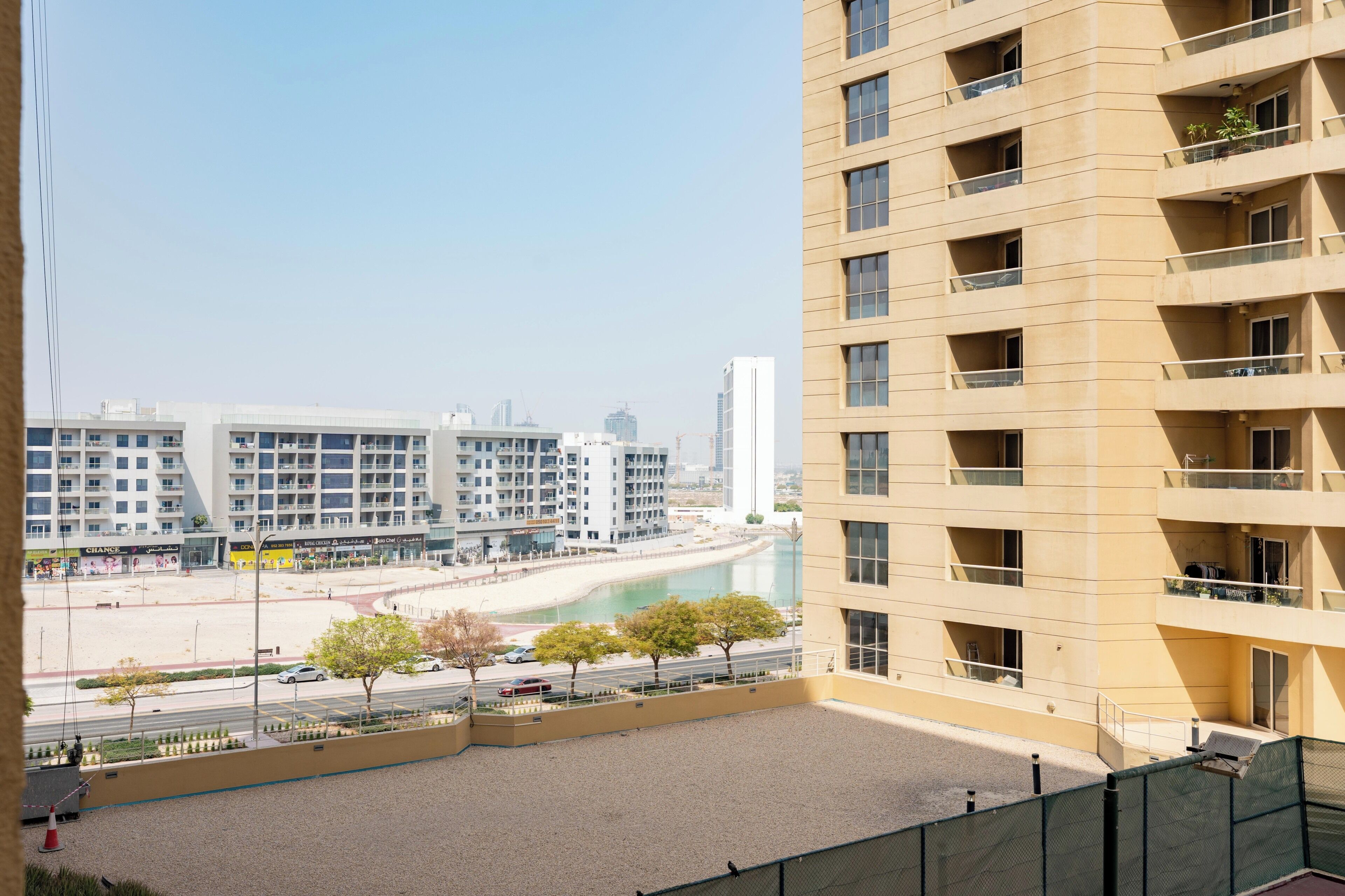 A high-rise building with multiple balconies, a view of a beach, and a clear sky.