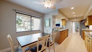 A modern kitchen with wooden cabinets, a dining area with a table and chairs, and a large window. - Significant Golf Views from this 3-Bedroom Fazio Villa (Hilton Head)