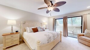 A bedroom with a bed, bedside tables, a ceiling fan, and a balcony with curtains. - Significant Golf Views from this 3-Bedroom Fazio Villa (Hilton Head)