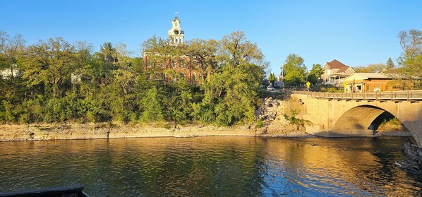 A stone bridge over a river with a clock tower in the background. - 2-bedroom apartment in pleasant Elkader with AC and charm (Elkader)